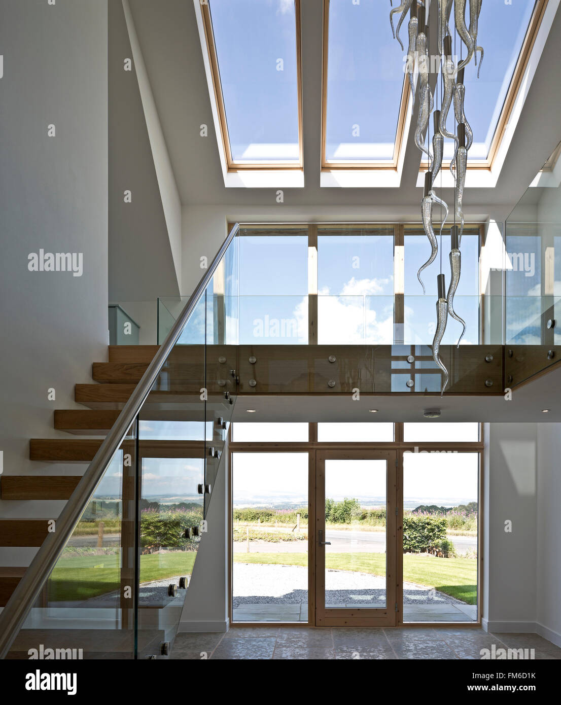 Una vista interna di una moderna struttura residenziale chiamato Amor House, a Gleneagles, mostrando la hall di ingresso e scala, con grandi finestre di vetro. Foto Stock