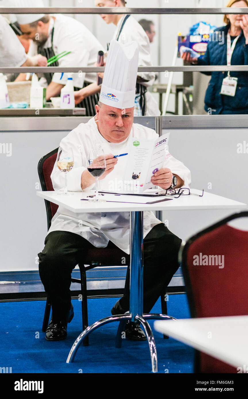 Un capo chef controlla il menu in un ristorante.mentre è seduto in un ristorante tavola con un bicchiere di vino. Foto Stock
