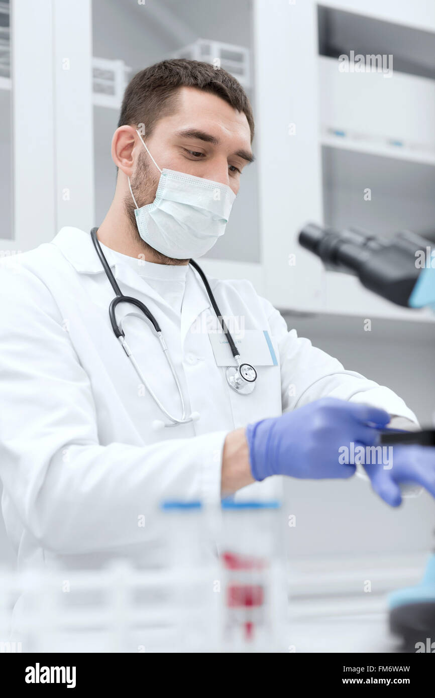 Giovane maschio scienziato indossando i guanti in laboratorio Foto Stock