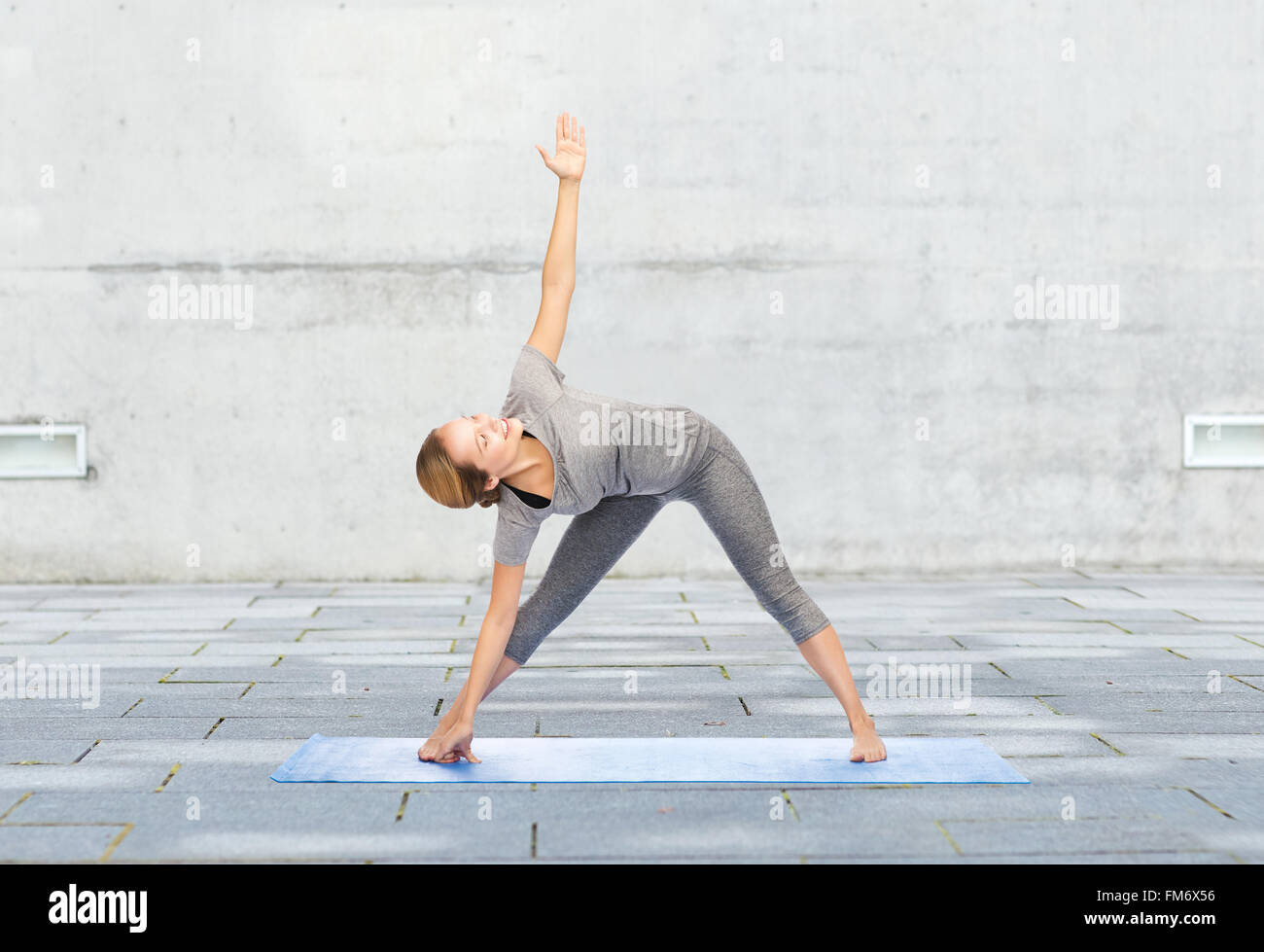 Donna che fa il triangolo di yoga pone sul tappeto Foto Stock