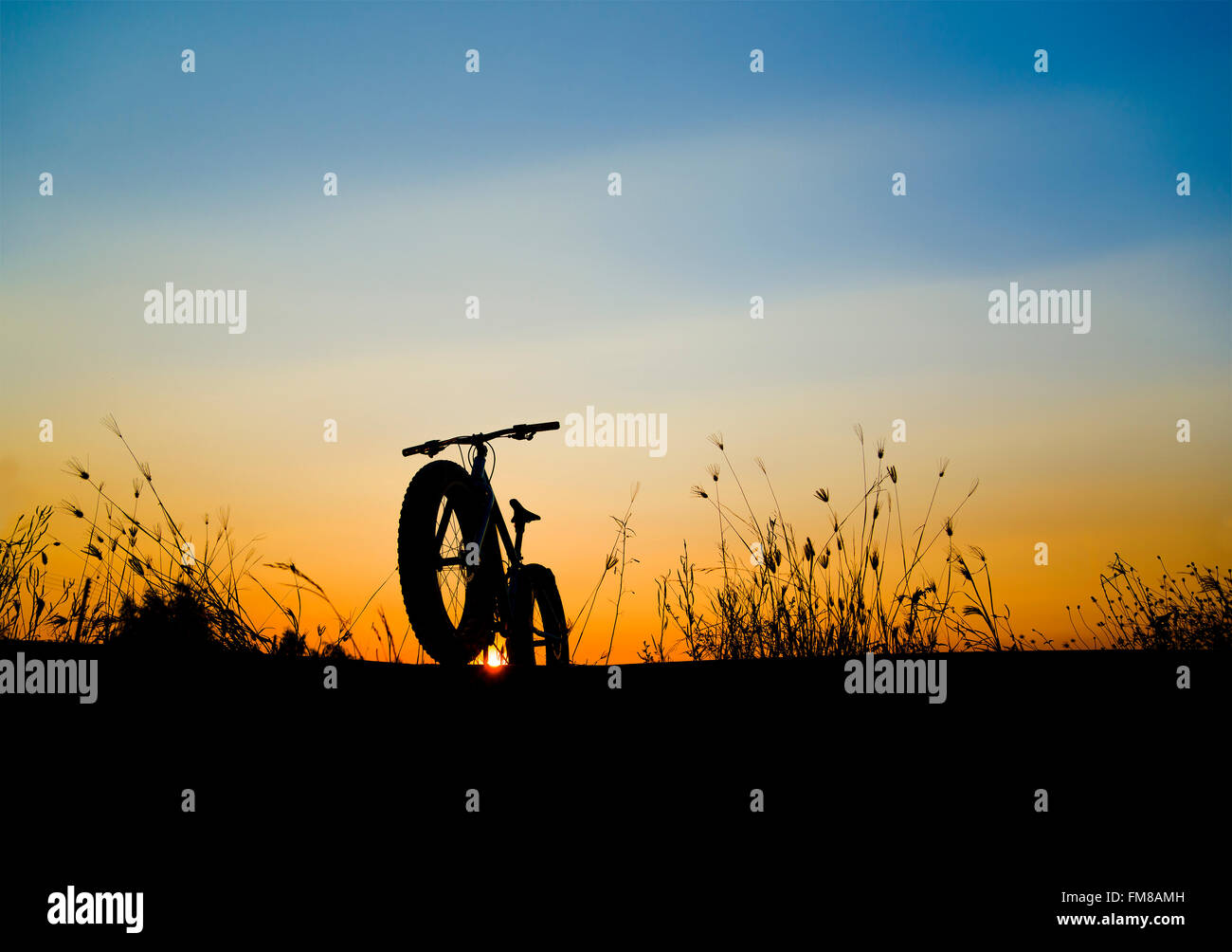 Bel tramonto Cielo e mountain bike , silhouette silhouette fat bike Foto Stock