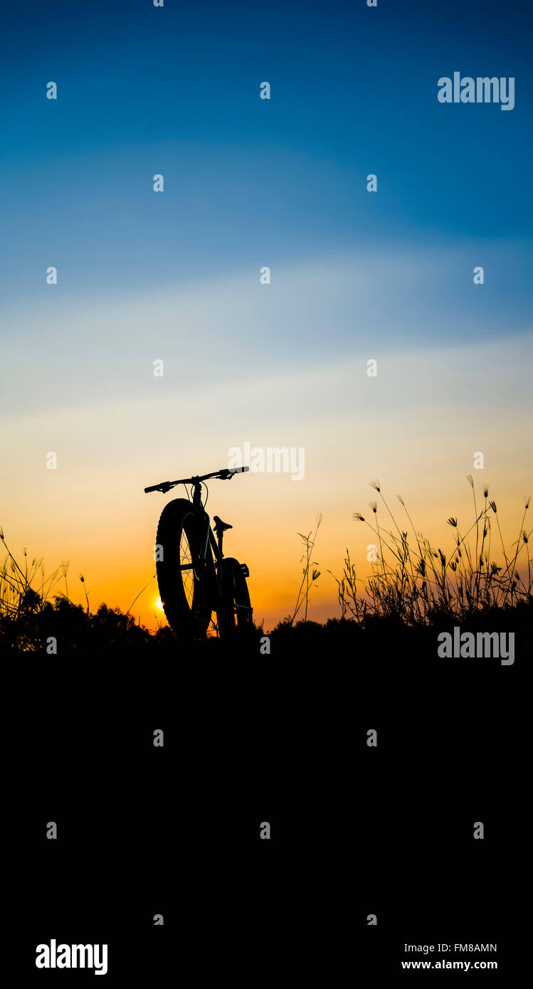 Bel tramonto Cielo e mountain bike , silhouette silhouette fat bike Foto Stock