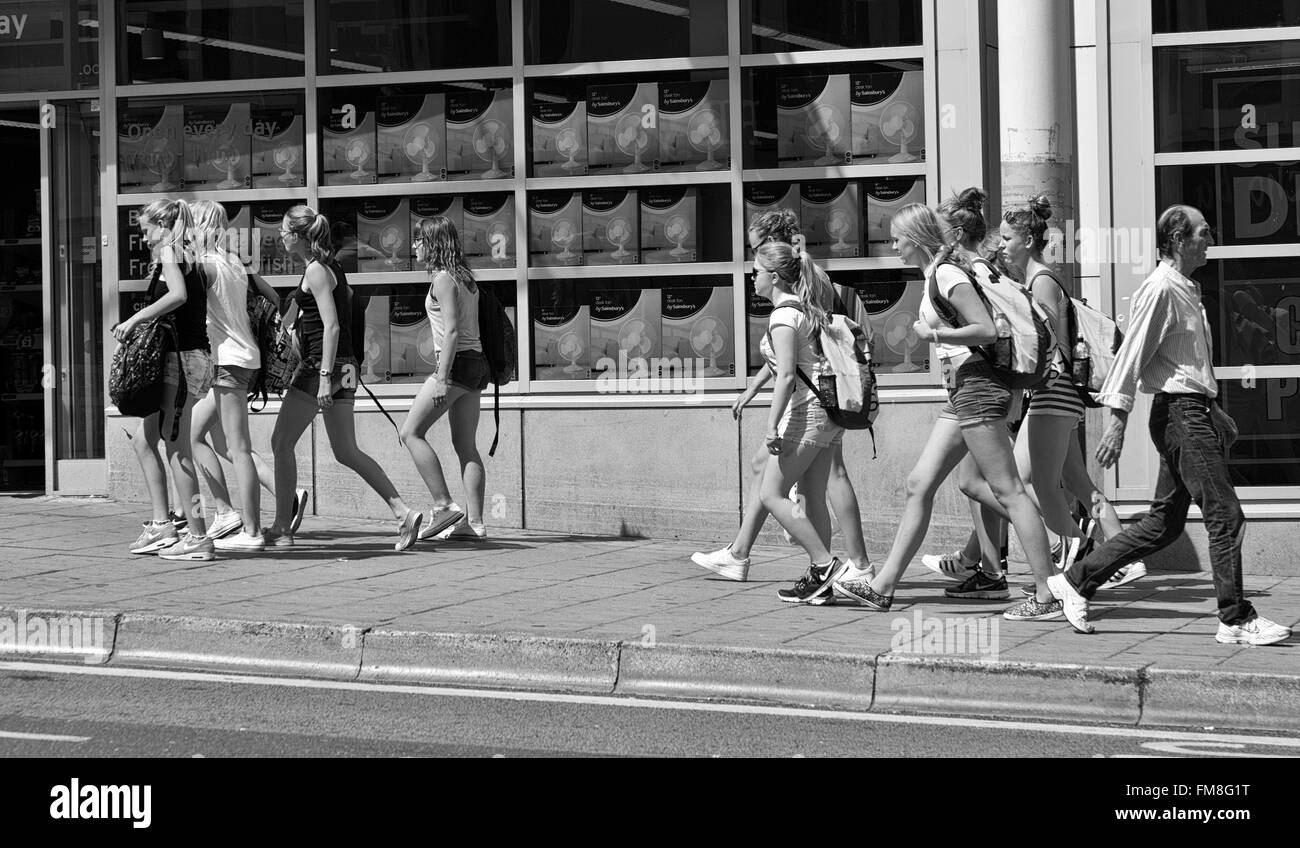 Barbuto unattracive uomo passa nella direzione opposta a quella del grande gruppo di ragazze attraenti in pantaloncini corti di Brighton e Hove Regno Unito Foto Stock