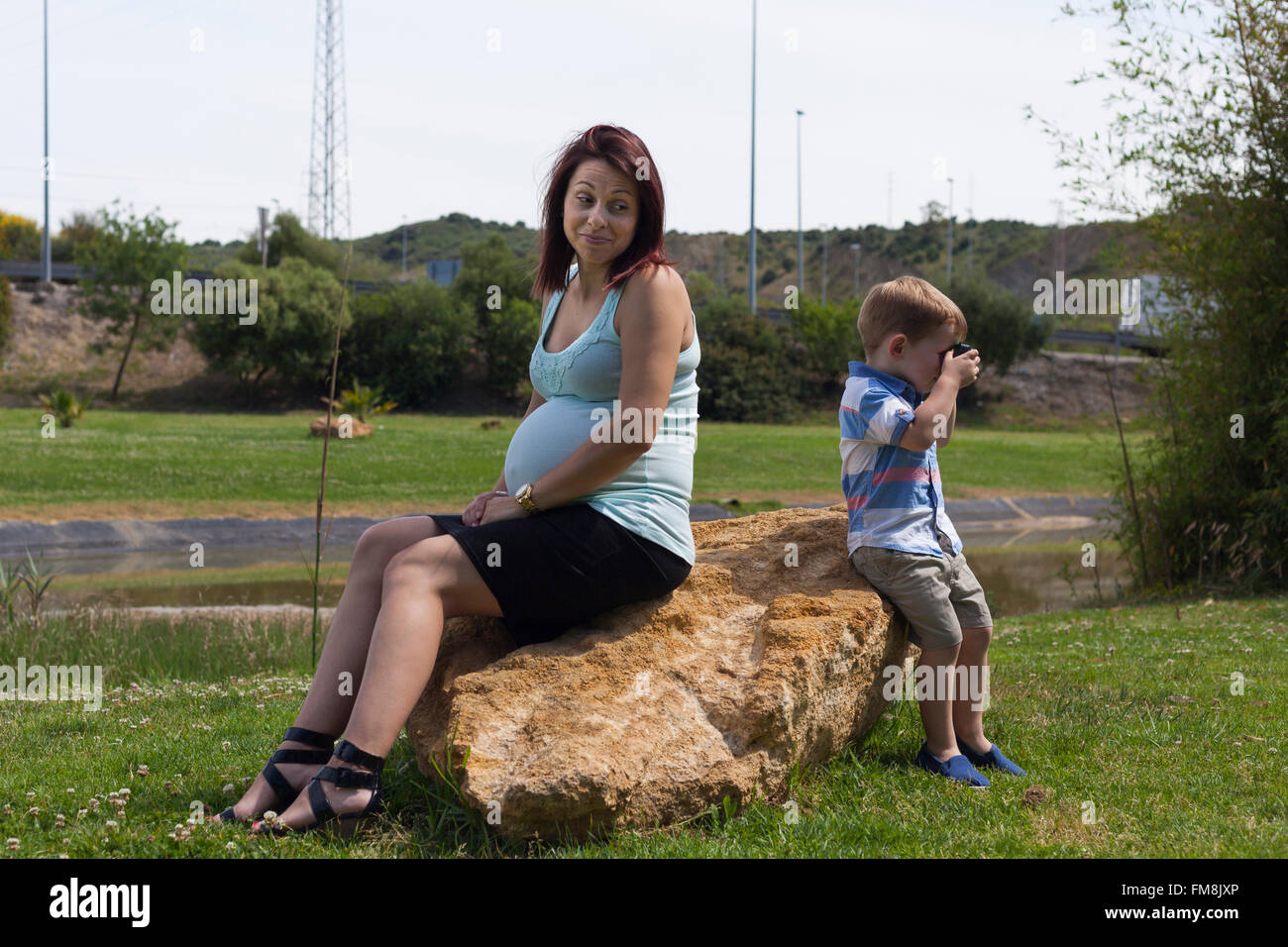 La donna incinta e il bambino ragazzo seduto di schiena all'esterno. Foto Stock