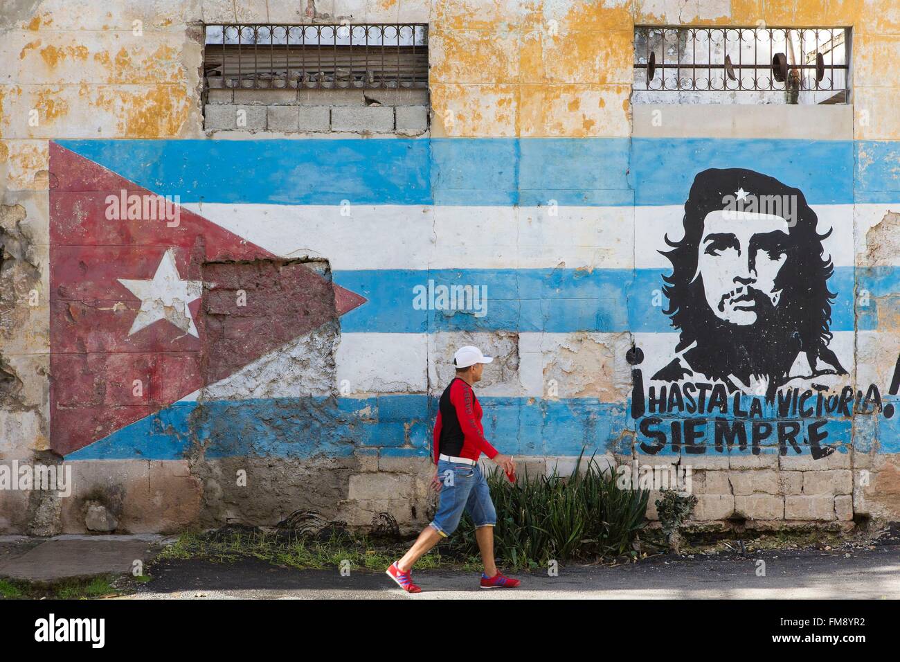 Cuba, Ciudad de la Habana Province, La Havana, Centro Habana distretto, uomo a camminare da una facciata dipinta con una bandiera di Cuba e Che Guevara (Copyright Alberto Diaz Gutierrez alias Korda) nel centro Habana Foto Stock