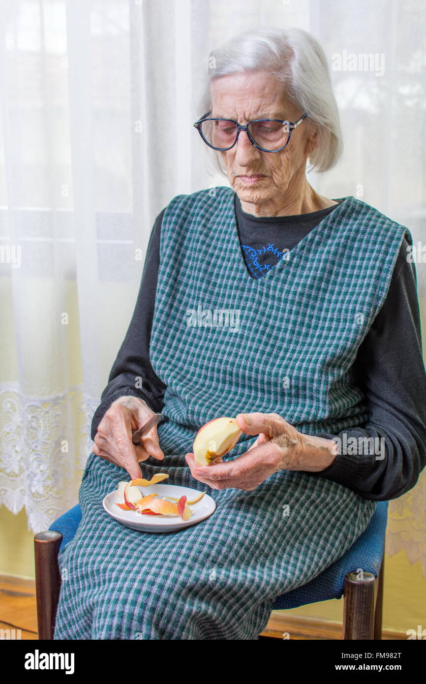 Novanta anni nonna la tranciatura e la sfogliatura di un Apple in ambienti interni Foto Stock