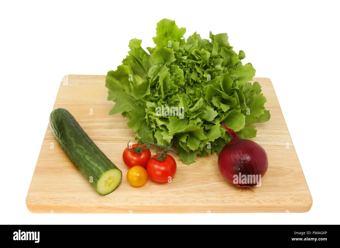 Ingredienti insalata di lattuga, cetriolo, pomodori e una cipolla rossa su un tagliere di legno isolata contro bianco Foto Stock