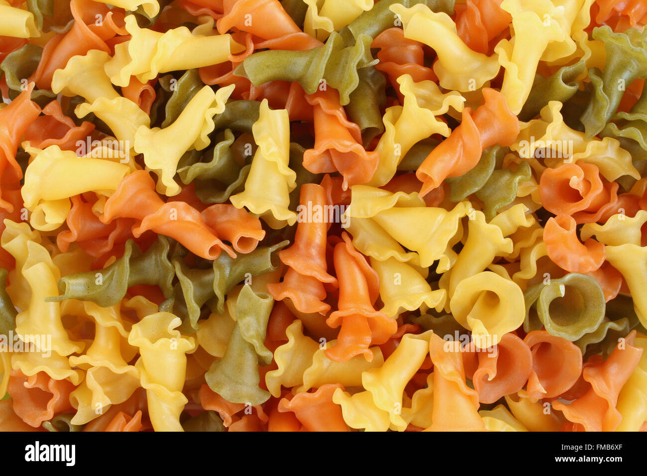 Sfondo di cibo - non cotte a tre Campanelle colorate la pasta di semola di grano duro con spinaci e pomodoro Foto Stock