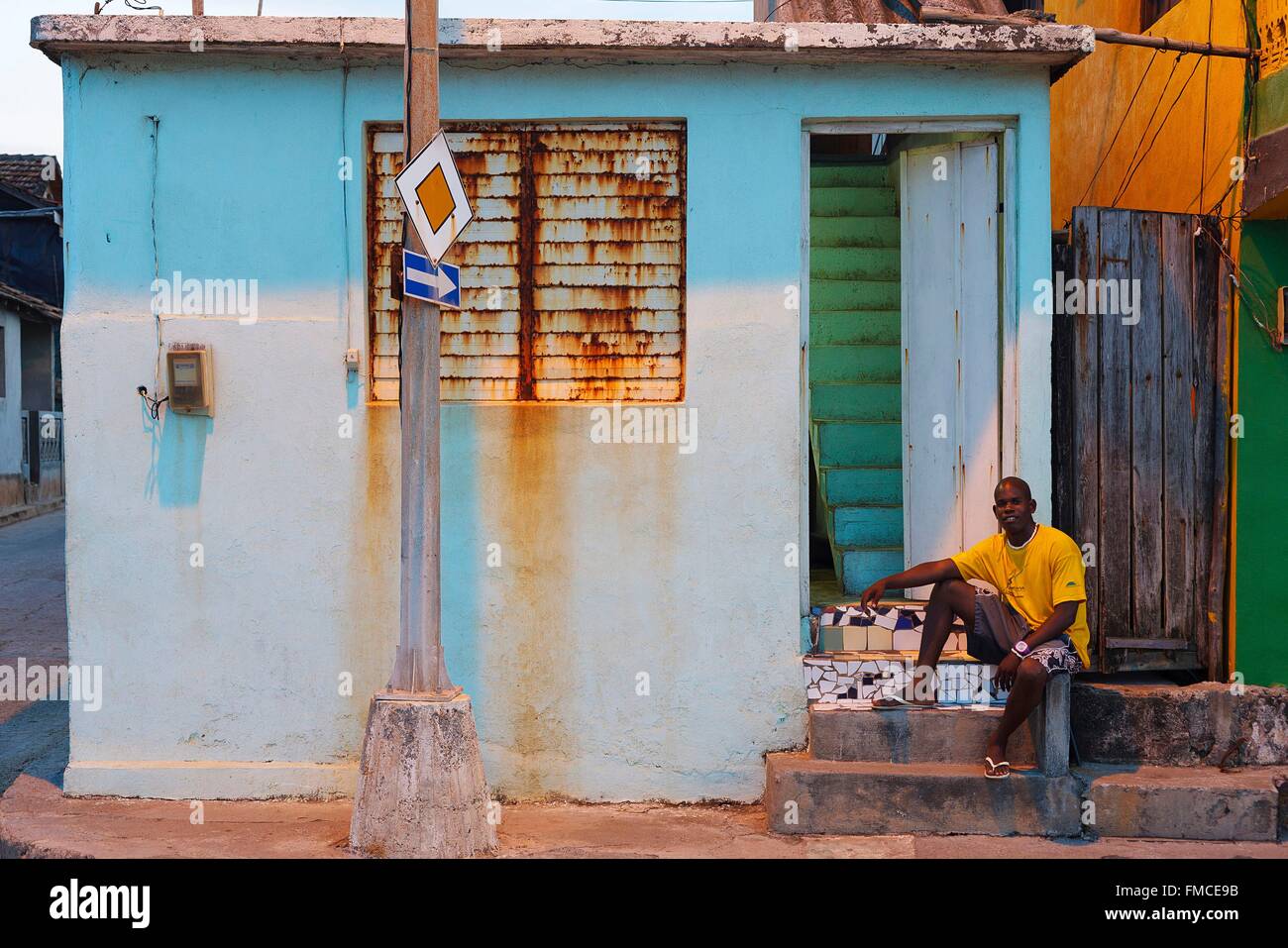 Cuba, Guantanamo Baracoa, uomo seduto di fronte a casa sua parete sbiadito Foto Stock