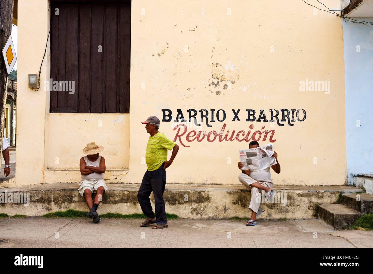 Cuba, Guantanamo Baracoa, gli uomini in strada al di fuori di un edificio in un giallo pallido parete Foto Stock