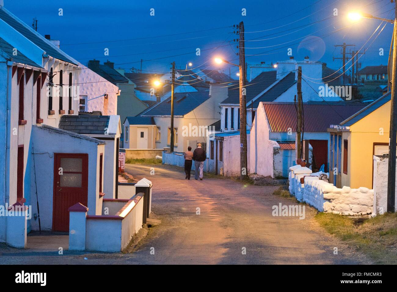 Irlanda, County Donegal, Tory Island, un uomo e una donna a piedi nel villaggio al crepuscolo Foto Stock