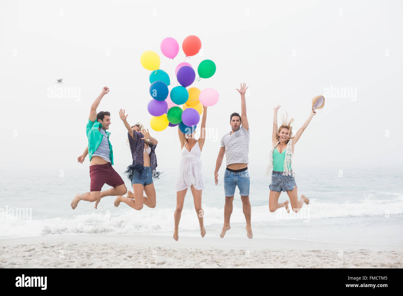 Gruppo di amici il salto sulla spiaggia con palloncini Foto stock - Alamy