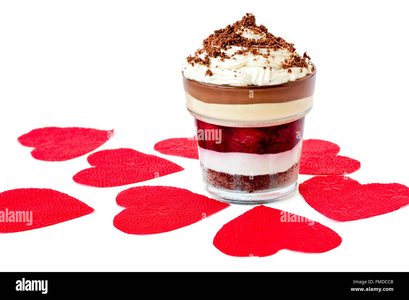 Layered dessert con biscotti sbriciolati sulla parte superiore a forma di cuore rosso tovaglioli isolato su bianco Foto Stock
