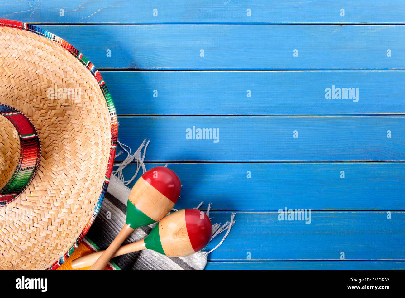 Sombrero messicano e maracas con tradizionale serape coperta prevista su un vecchio blu dipinta in legno di pino piano. Spazio per la copia. Foto Stock