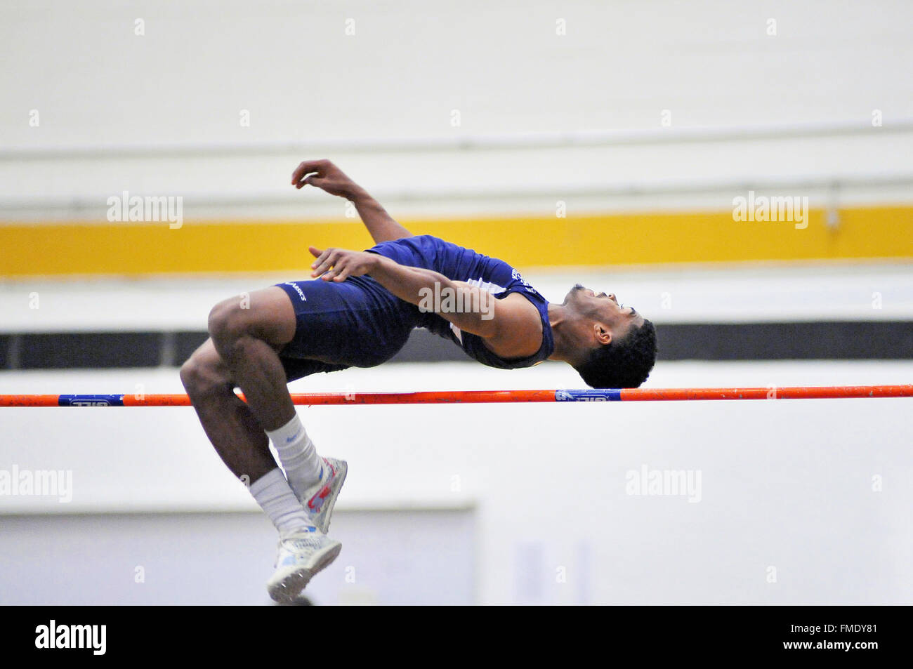 Una scuola di atleta di tentare di eliminare il salto in alto bar a un incontro al coperto. Stati Uniti d'America. Foto Stock