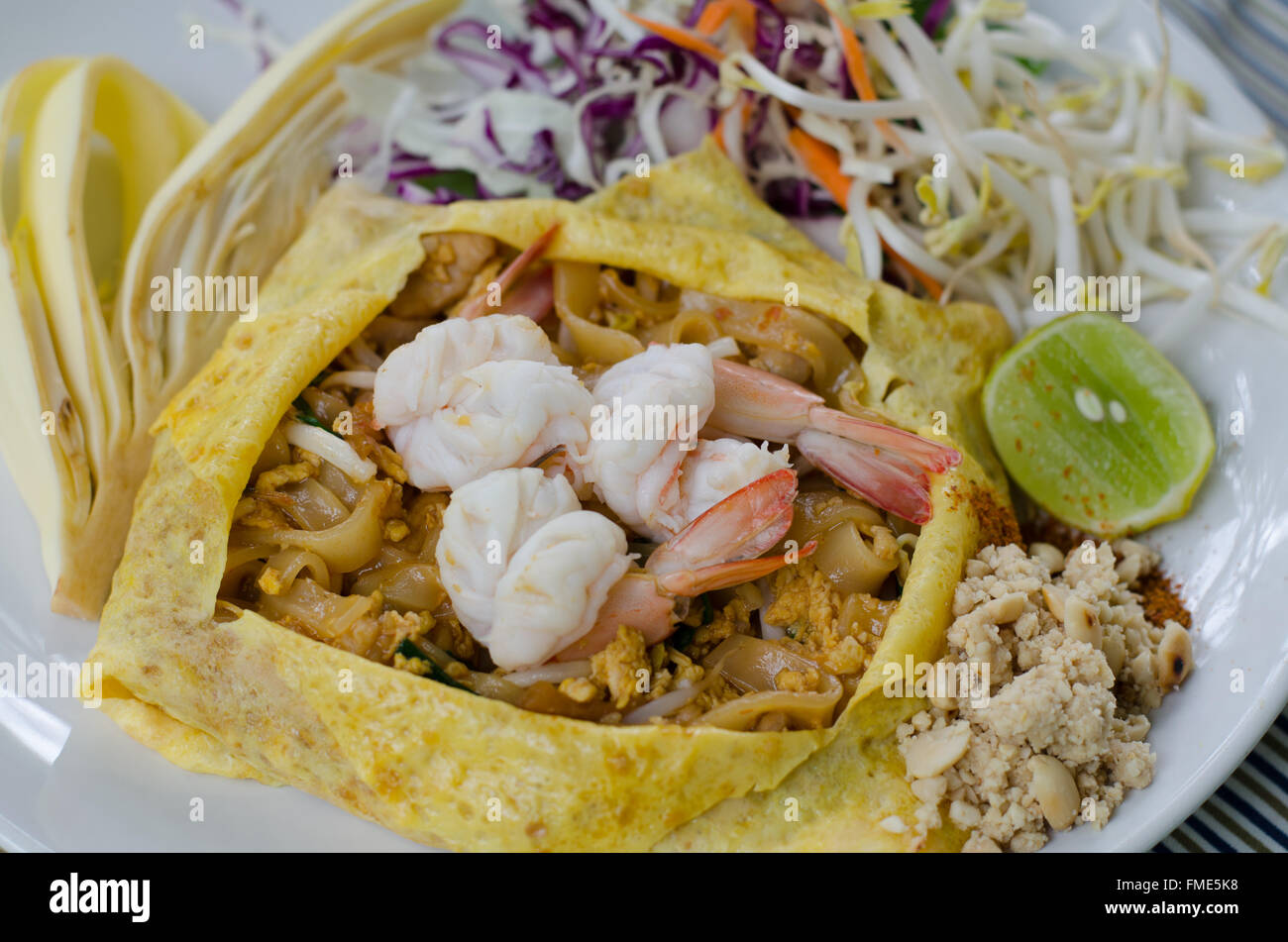 Il cibo thai Pad Thai , STIR FRY tagliatelle con carne di maiale.avvolgere le uova sulla piastra bianca decorata con condimenti vari Foto Stock