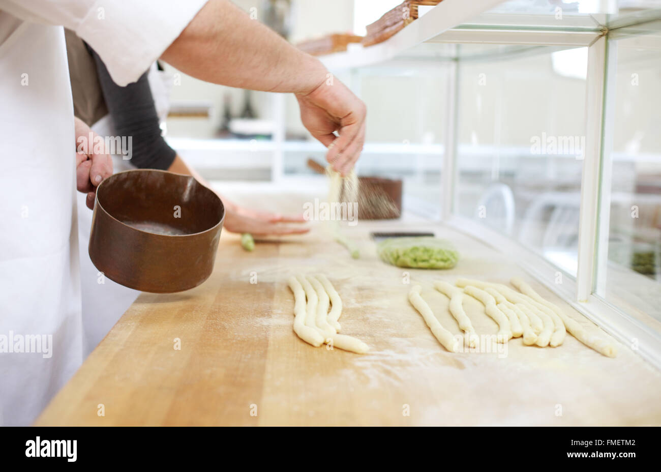 Uno chef polveri preparate verde e bianca di pasta su una superficie in legno con farina di semola. Foto Stock