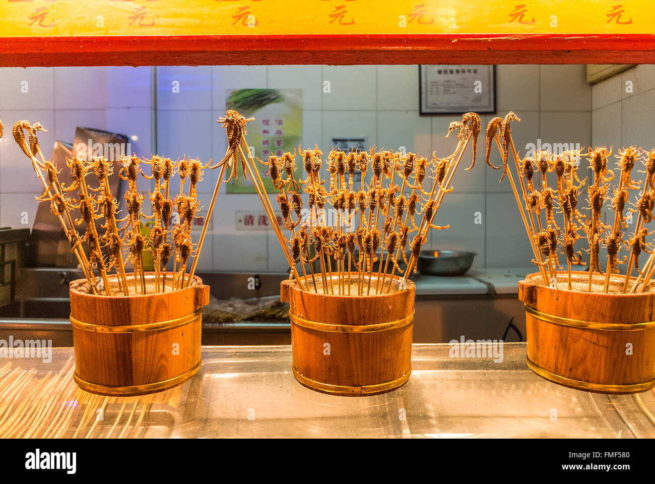 Scorpioni e altri insetti su spiedi vengono offerti da un venditore in bancarelle del mercato di Wangfujing Snack Street Foto Stock