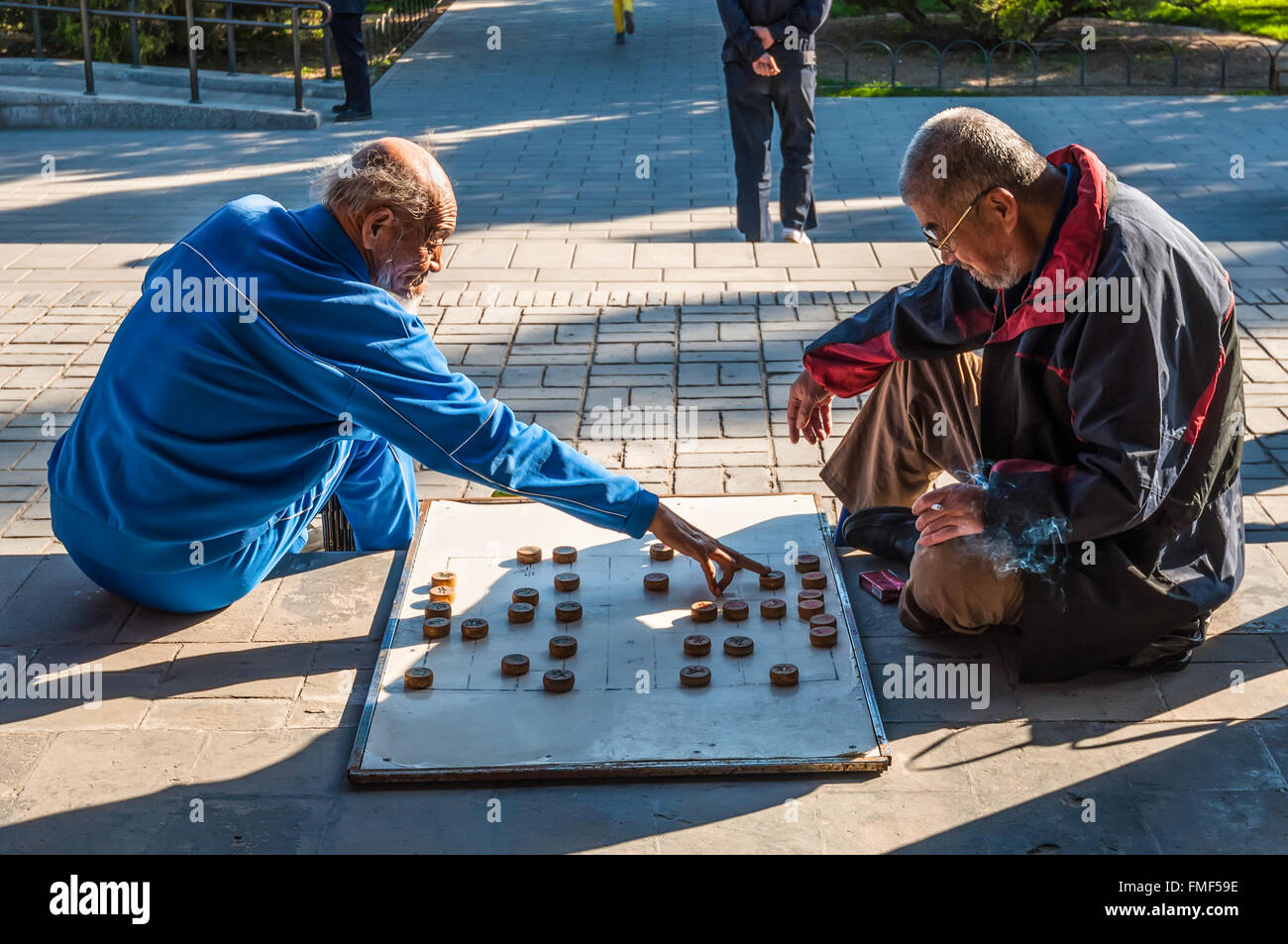 Anziani uomini cinesi giocando a scacchi cinesi chiamato Xiangqi in un parco al di fuori del tempio del cielo a Pechino, Cina Foto Stock