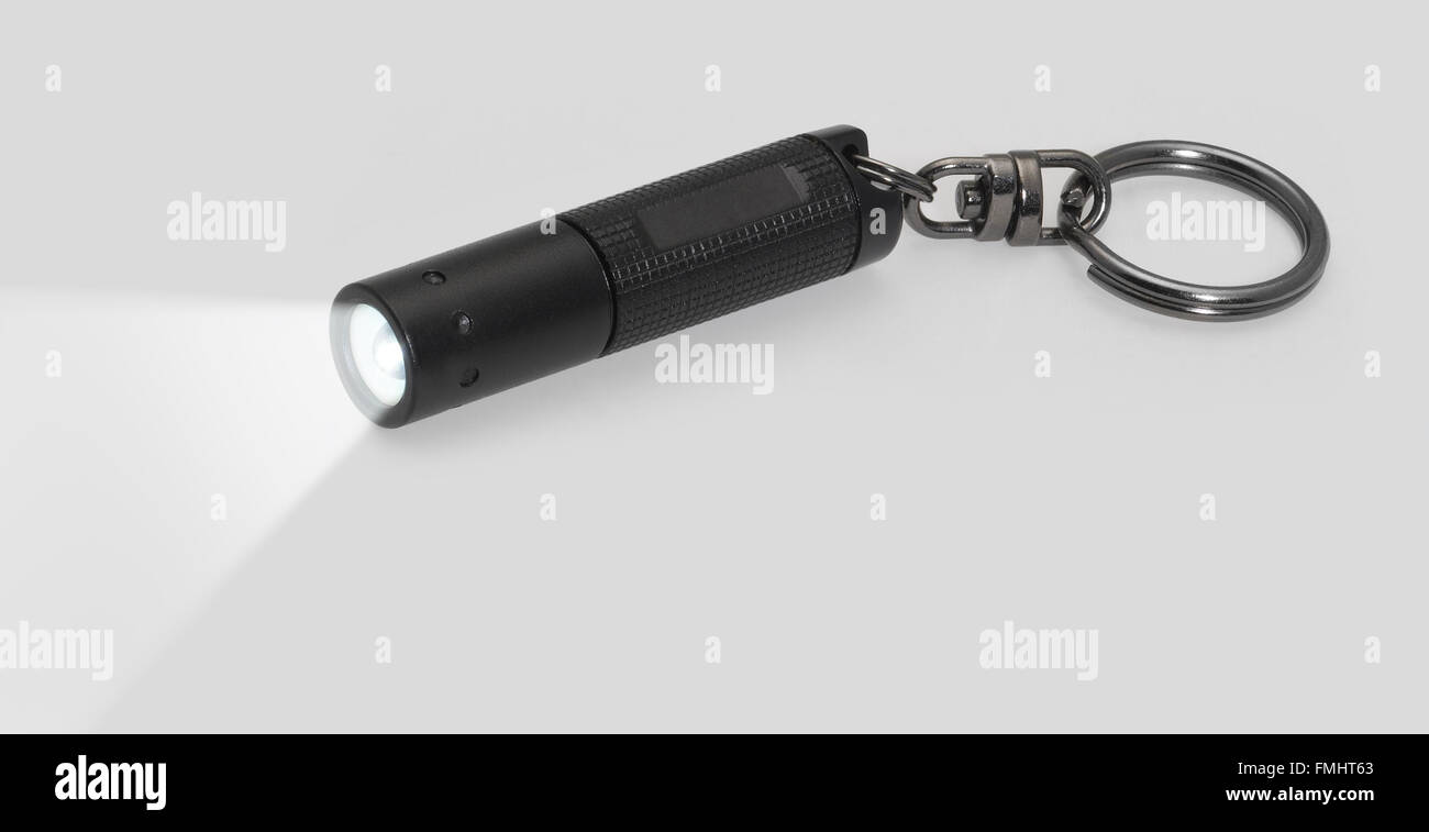 Piccola lampada tascabile con raggio di luce nella parte posteriore grigia Foto Stock