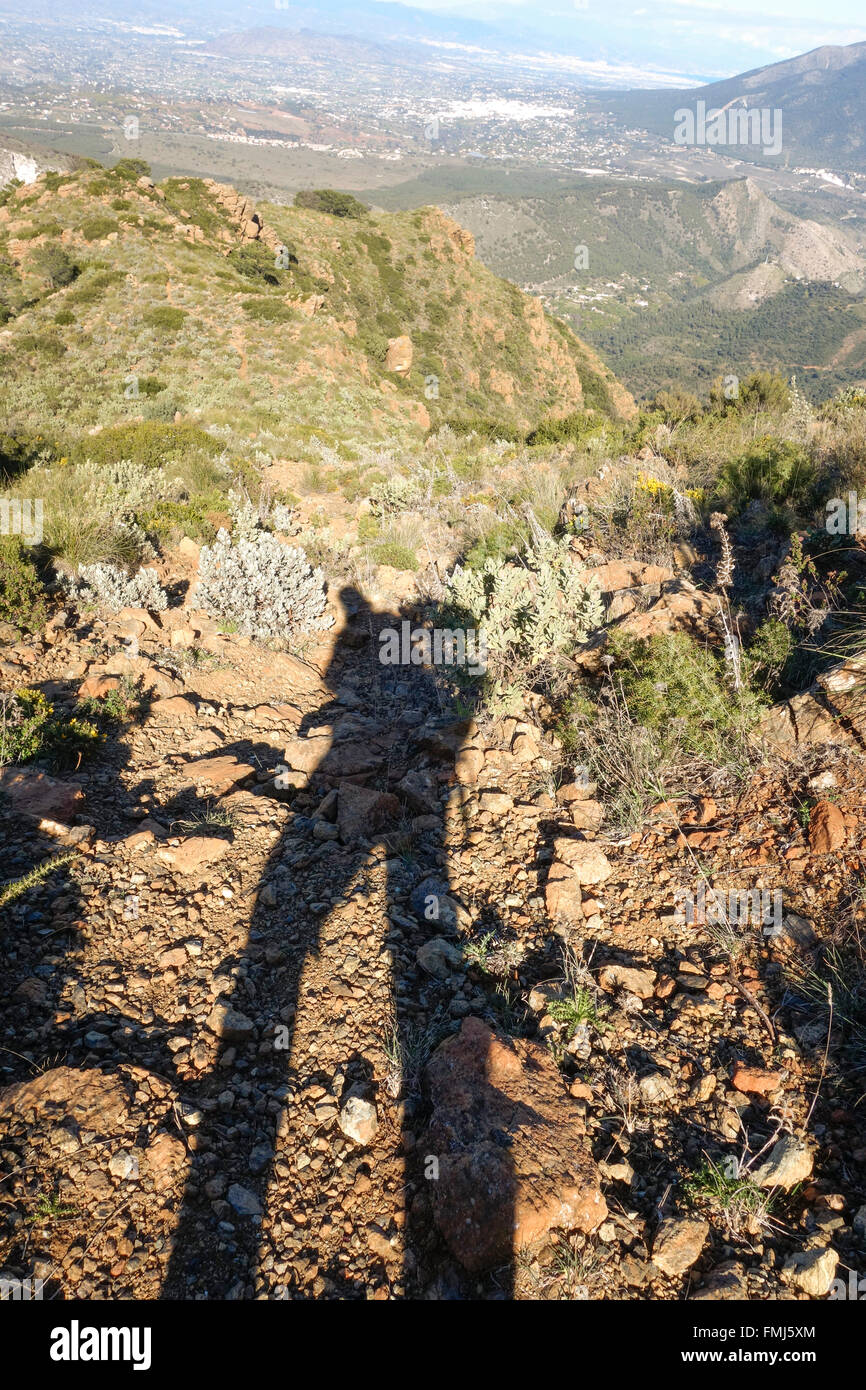 Lunga ombra di un uomo cade sul sentiero roccioso in montagna. Malaga, Spagna. Foto Stock