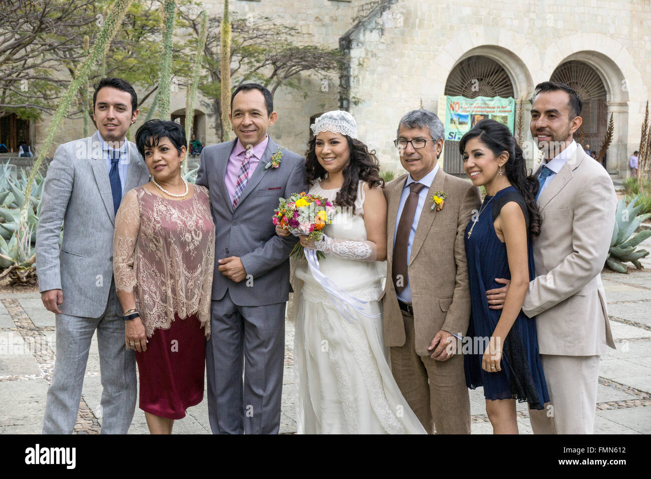 Mexican party di nozze posa per il ritratto sulla chiesa di Santo Domingo Plaza con sorridente sposa azienda piccoli bouquet di fiori di primavera Foto Stock