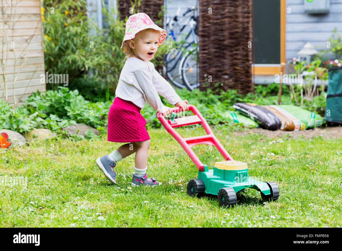 Bambino e bambina in giardino con toy tosaerba Foto Stock