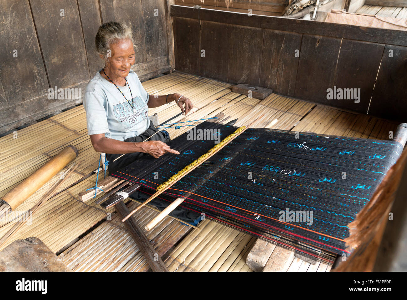 Donna anziana tessitura stoffa ikat mostrando, tradizionale villaggio Ngada Bena, Bajawa, Flores, Indonesia Foto Stock
