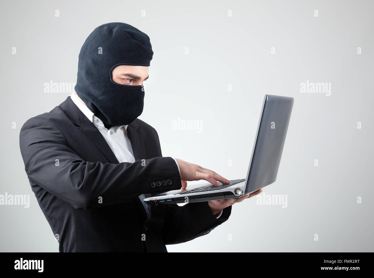 Ritratto di un hacker con passamontagna contro uno sfondo grigio Foto stock  - Alamy