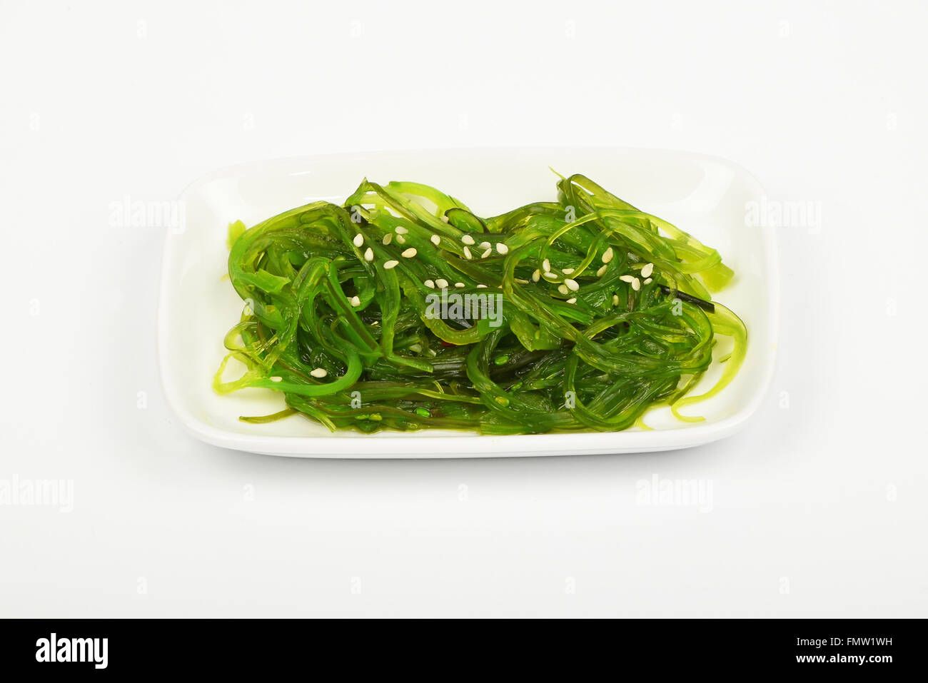 Porzione di tradizionali asiatici avidità marinato insalata di alghe marine aperitivo sul piccolo piatto bianco sopra la piastra di sfondo bianca, angolo alto Foto Stock