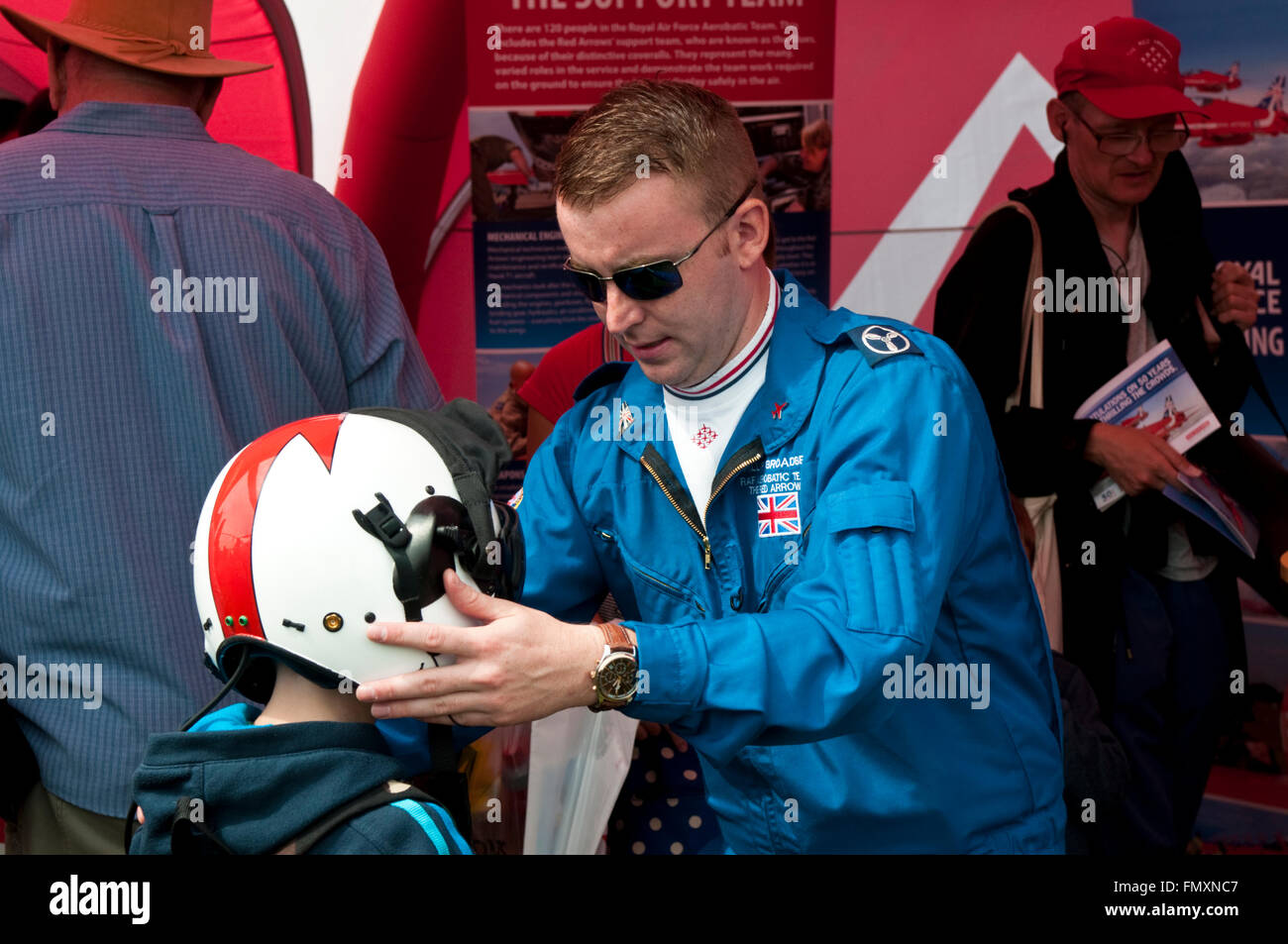 Un membro delle frecce rosse si inserisce un casco di volo su un bambino a Eastbourne Air Show Foto Stock