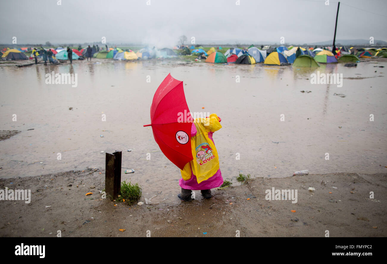 Idomeni, Grecia. 13 Mar, 2016. Un rifugiato bambino gioca su un prato allagato durante un acquazzone nel campo profughi al confine tra la Grecia e la Macedonia in Idomeni, Grecia, 13 marzo 2016. Dopo la chiusura della rotta balcanica, circa 12.500 rifugiati vivono ora in questo campo. Foto: KAY NIETFELD/dpa/Alamy Live News Foto Stock