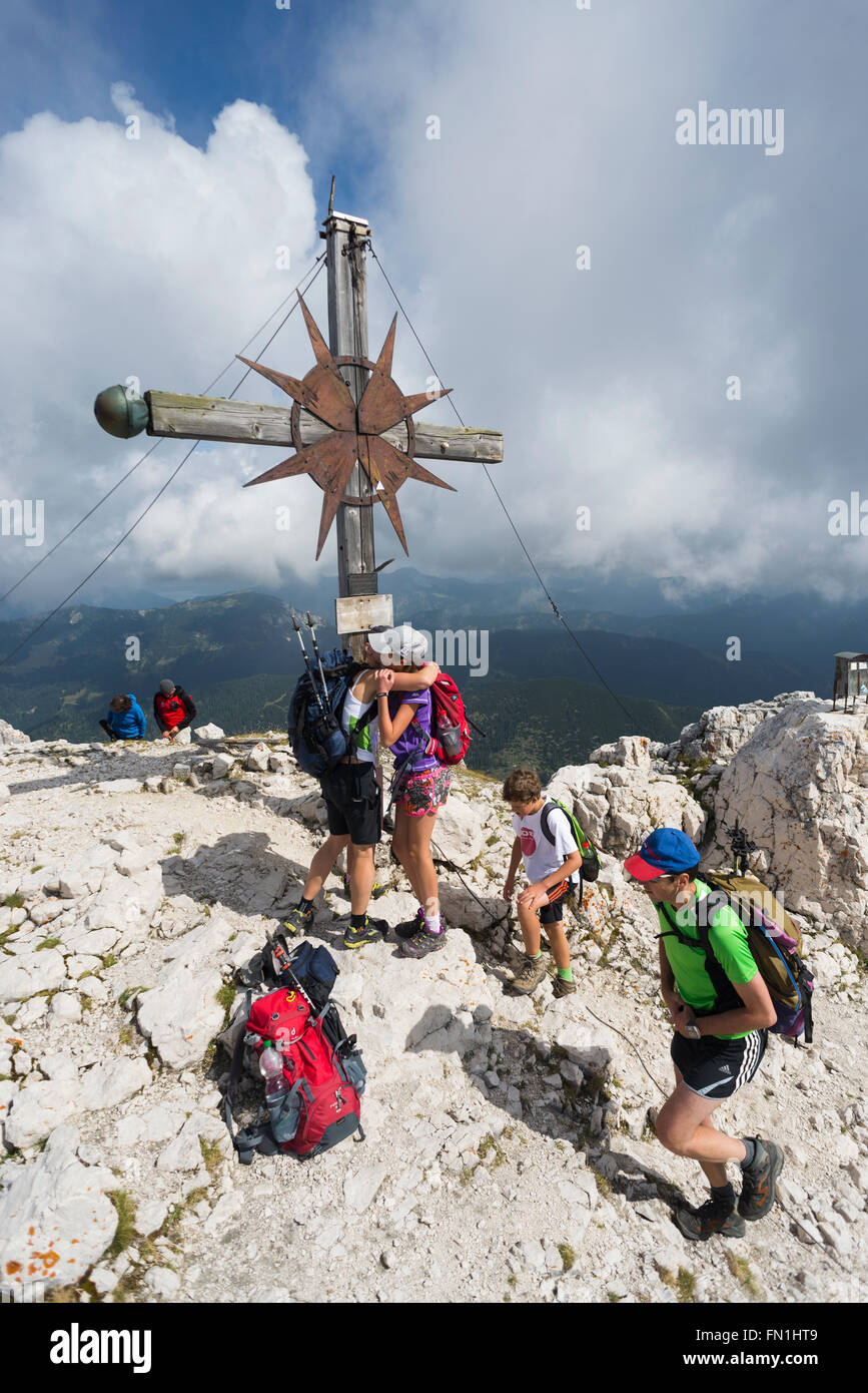 Madre e figlia di una famiglia abbracciarsi all'arrivo alla croce di vetta del Monte Guffert, Rofan, Tirolo, Austria Foto Stock