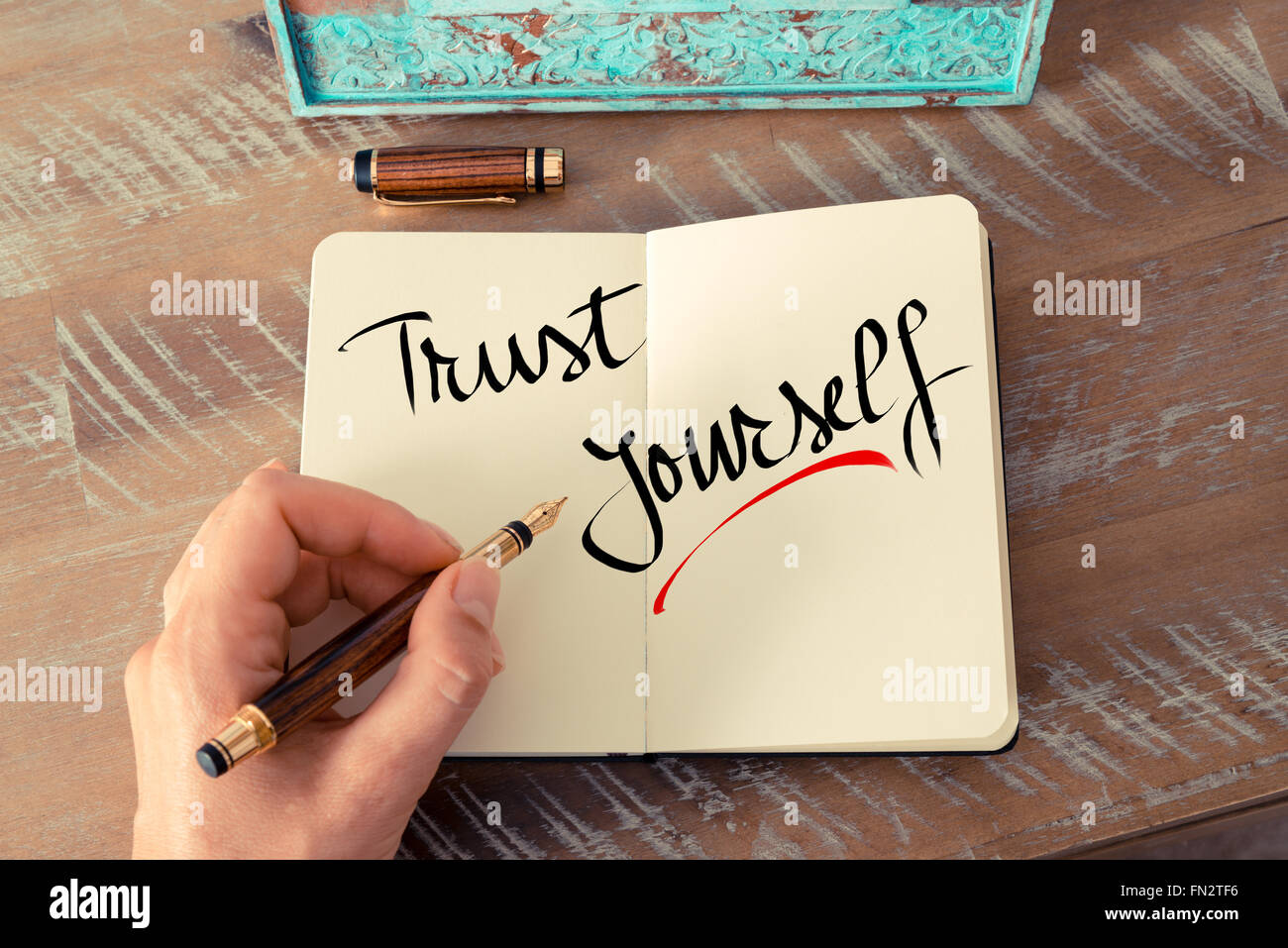 Effetto retrò e tonico immagine di una donna la scrittura a mano una nota con una penna stilografica su un notebook. Il testo scritto a mano Abbi fiducia in te stesso come business Concetto di immagine Foto Stock