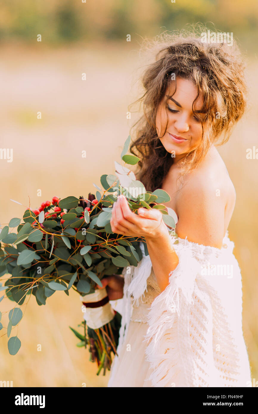 Bella Sposa in abito bianco detiene il bouquet e dolcemente sorridente Foto Stock