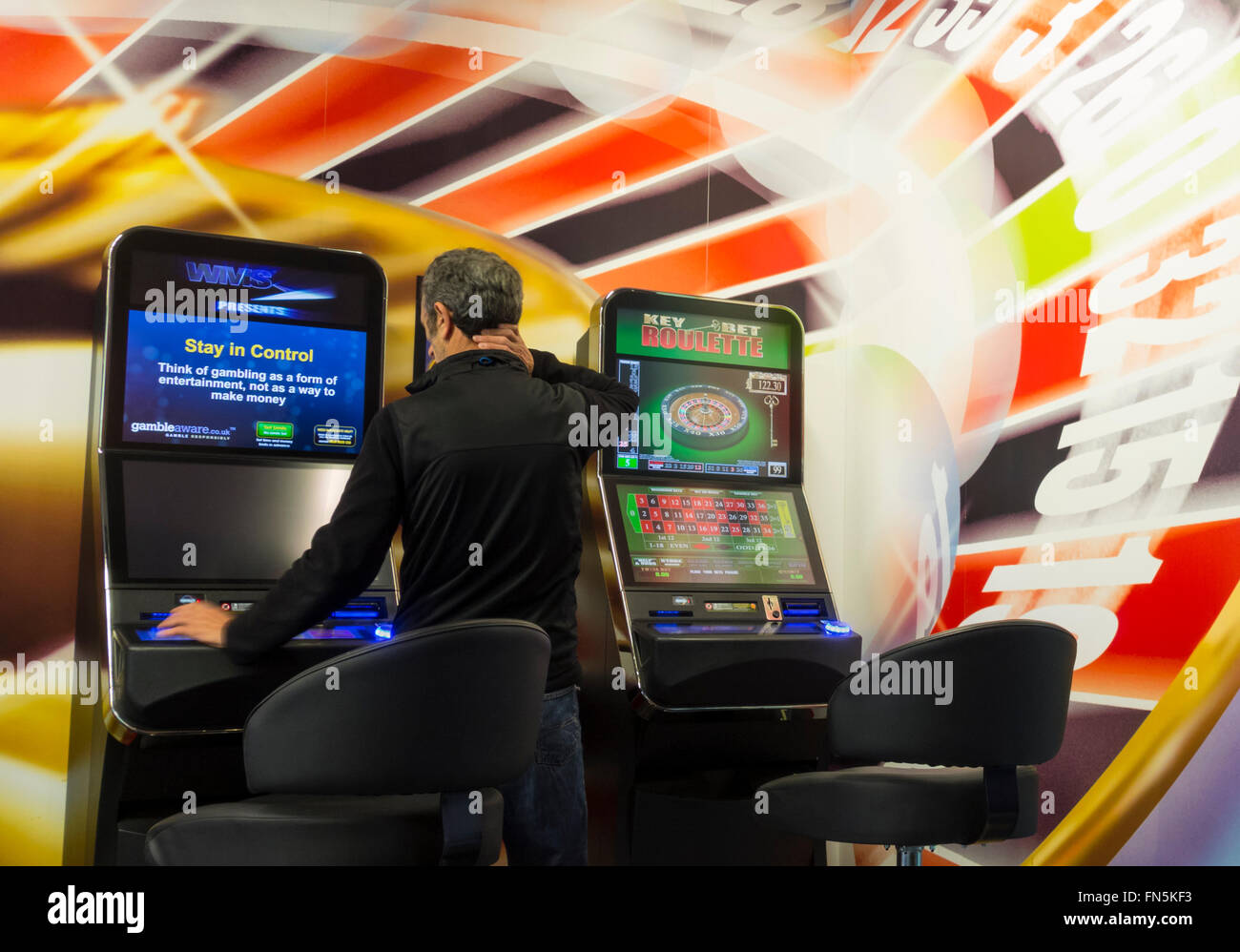 Uomo maturo utilizzando fixed odds betting terminale mostra soggiorno nel messaggio di controllo sullo schermo in Bookmakers. Inghilterra, Regno Unito Foto Stock