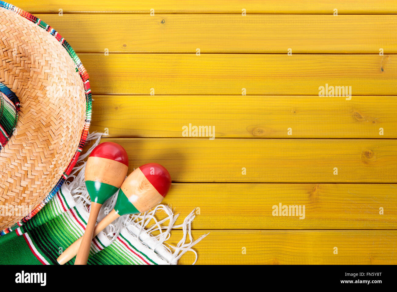 Sombrero messicano, le maracas e tradizionale coperta serape prevista su un dipinto di giallo in legno di pino piano. Spazio per la copia. Foto Stock