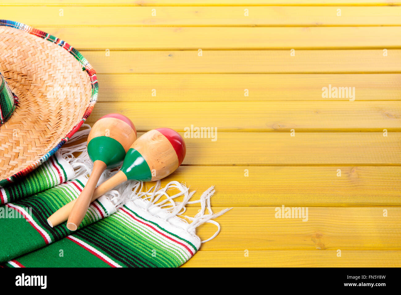 Sombrero messicano, le maracas e tradizionale coperta serape prevista su un dipinto di giallo in legno di pino piano. Spazio per la copia. Foto Stock