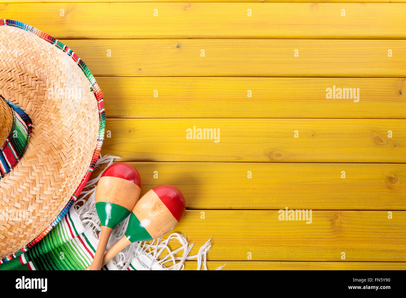 Sombrero messicano, le maracas e tradizionale coperta serape prevista su un dipinto di giallo in legno di pino piano. Foto Stock