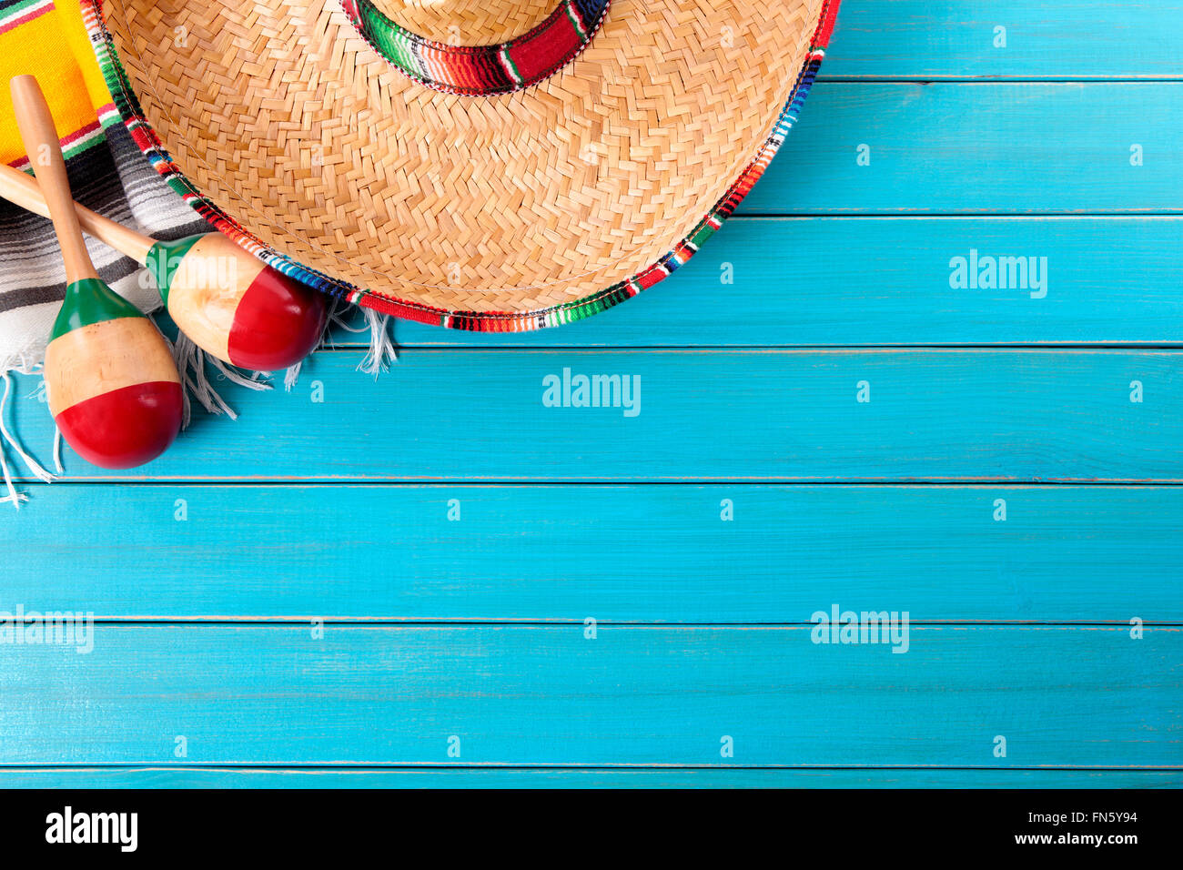 Sombrero messicano e maracas con tradizionale serape coperta prevista su un vecchio blu dipinta in legno di pino piano. Spazio per la copia. Foto Stock