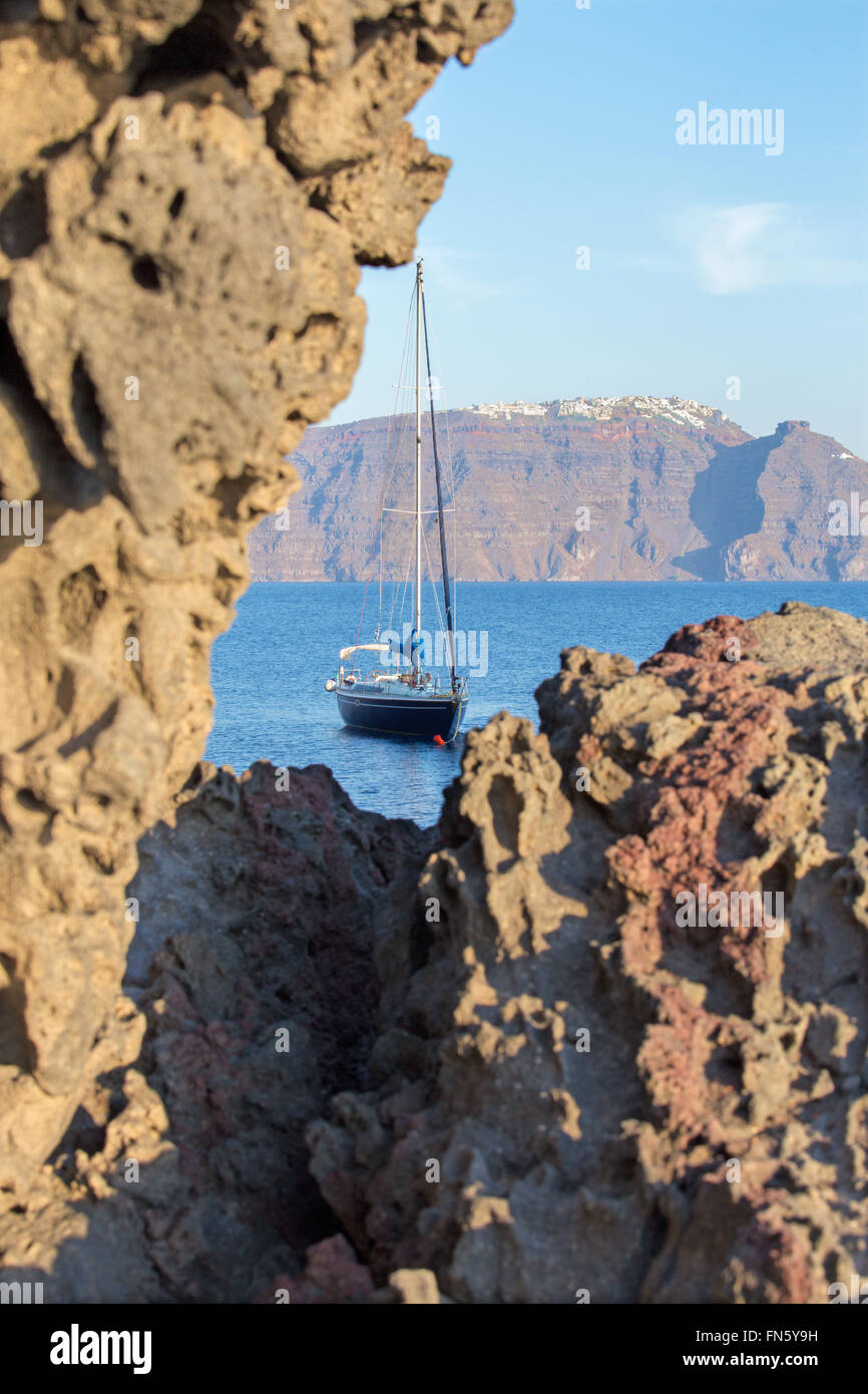 Santorini - il look di caldera tra i massi di pietra pomice con la Scaros Imerovigili ans in background e yacht Foto Stock