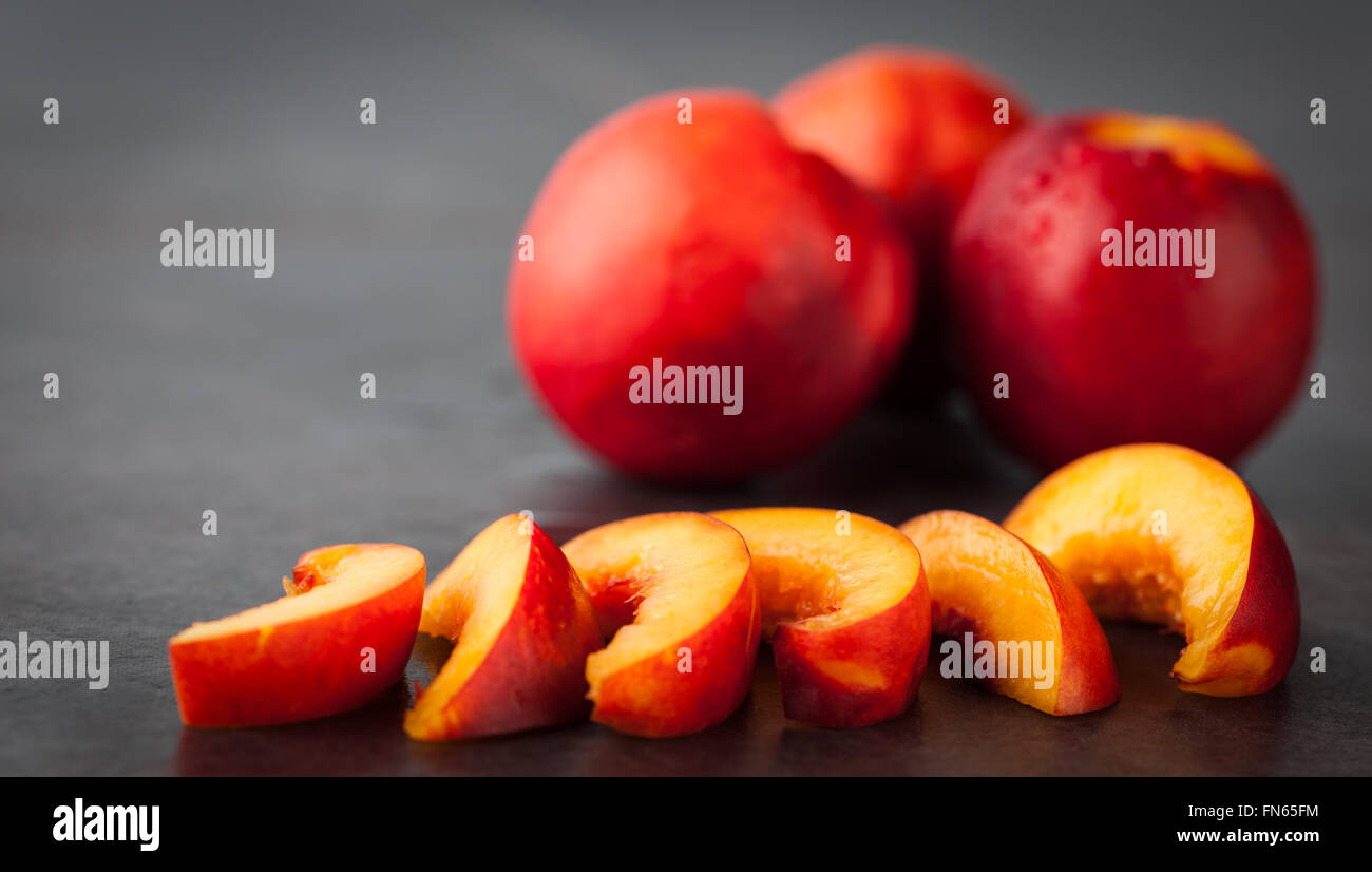 Giallo Nettarine Pesche - tutta la frutta e le fette su una schifezza scuro dello sfondo. Profondità di campo. Foto Stock