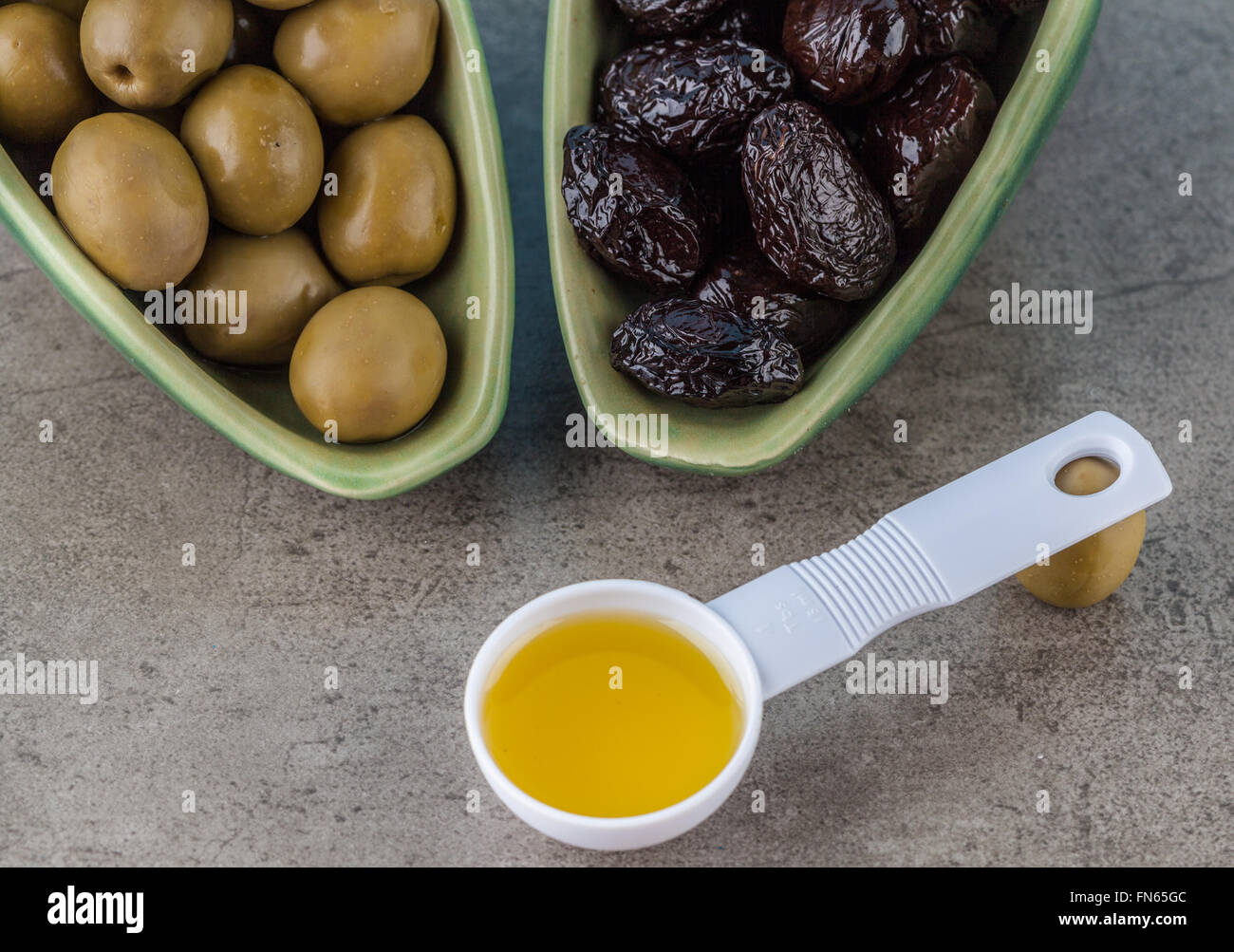Verde e nero olive salate e misurino con olio di oliva su sfondo a trama Foto Stock