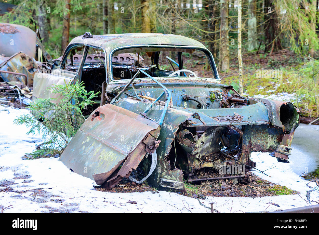 Un vecchio e molto degradate junk auto a sinistra in natura. Neve sulla terra. Foto Stock