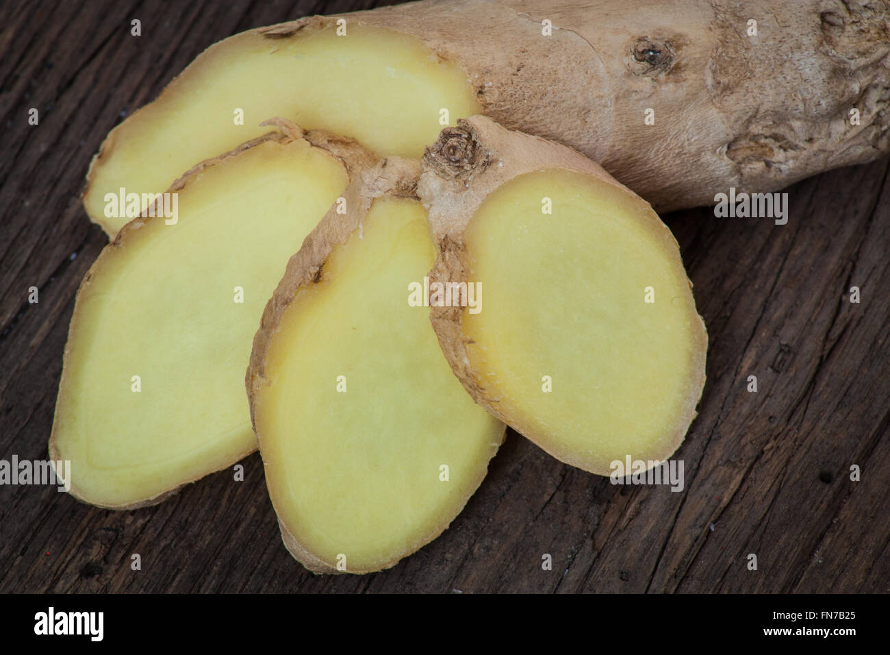 Tagliate a fette sottili di radice di zenzero su sfondo di legno Foto Stock