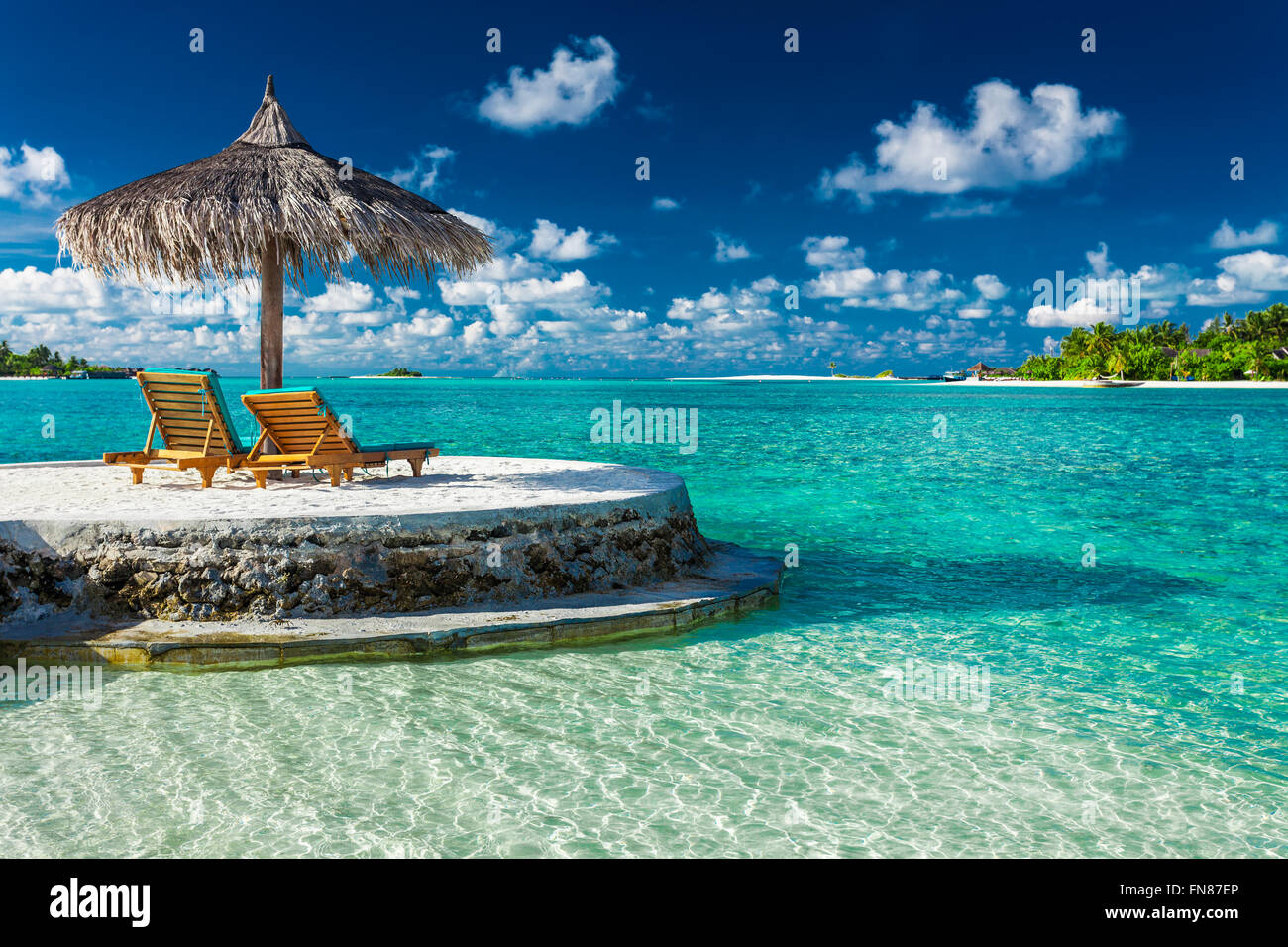 Due sedie a sdraio sotto ombrellone con vista oceano tropicale Maldive Foto Stock