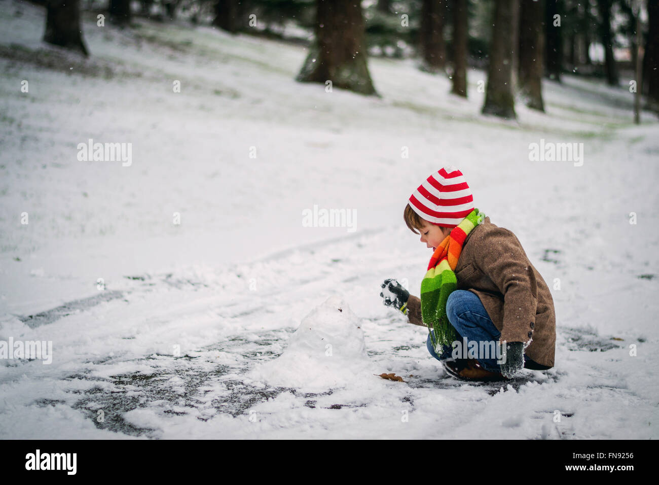 Ragazzo costruire un pupazzo di neve Foto Stock