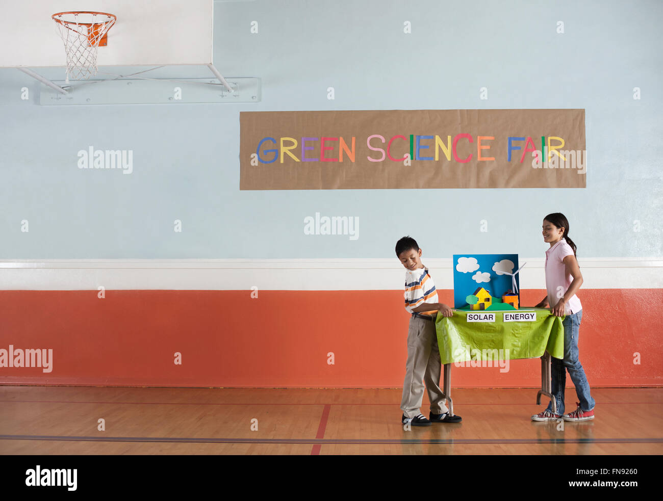 Un ragazzo e una ragazza che porta una tabella con una presentazione su energia solare, in corrispondenza di un verde Science Fair evento. Foto Stock