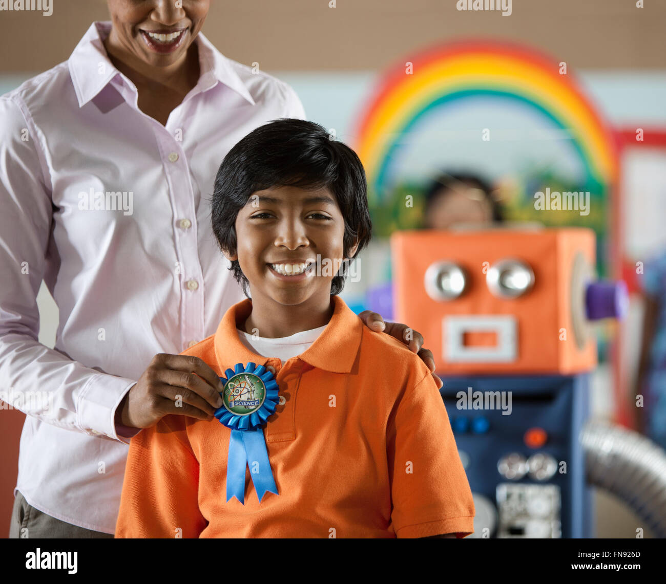 Una donna di aggiudicazione di un badge di rosette di uno studente a un evento educativo. Foto Stock