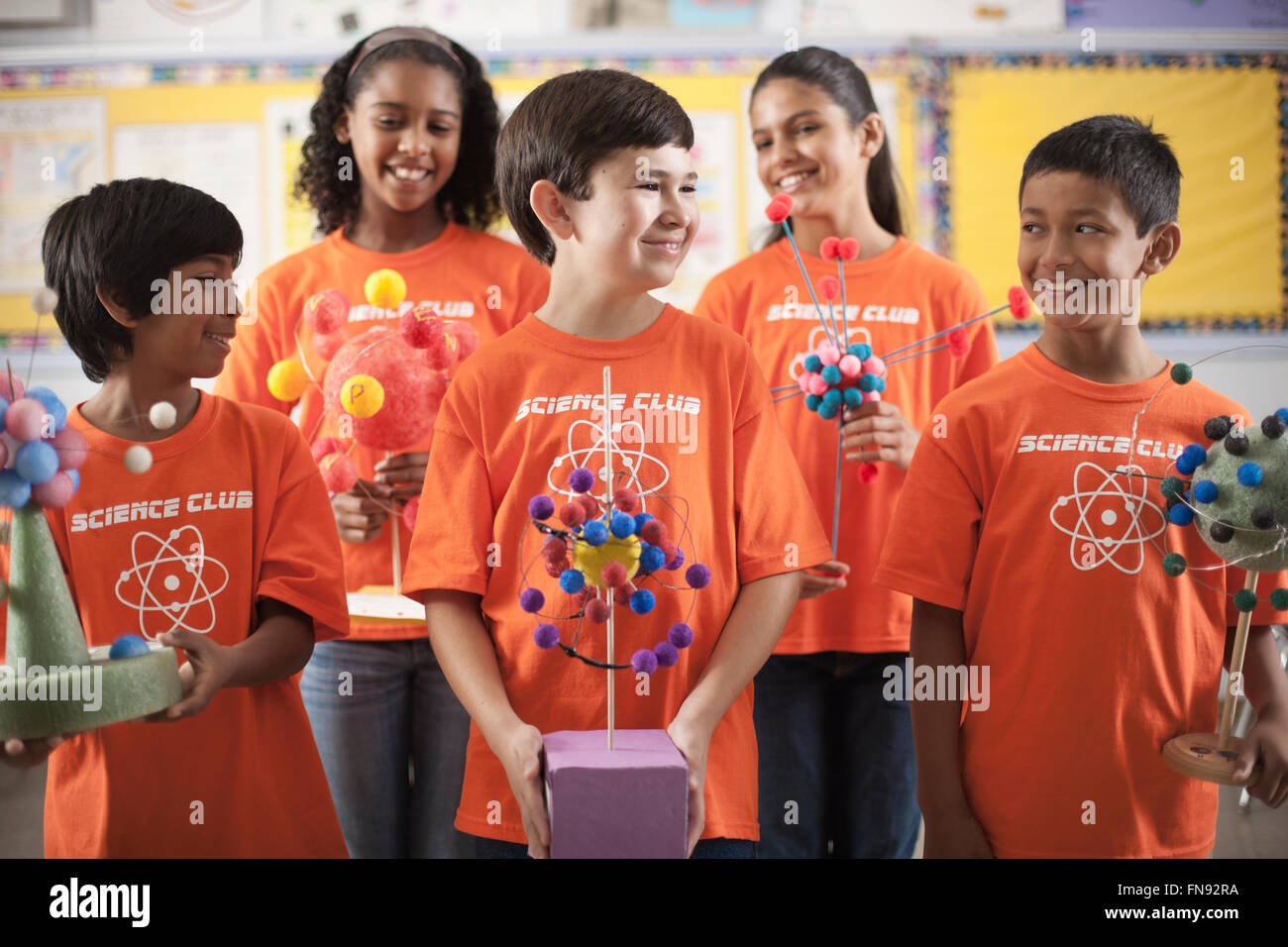 Un gruppo di ragazzi e ragazze che indossano il teeshirt della scienza Club, rendendo la struttura molecolare modelli. Foto Stock